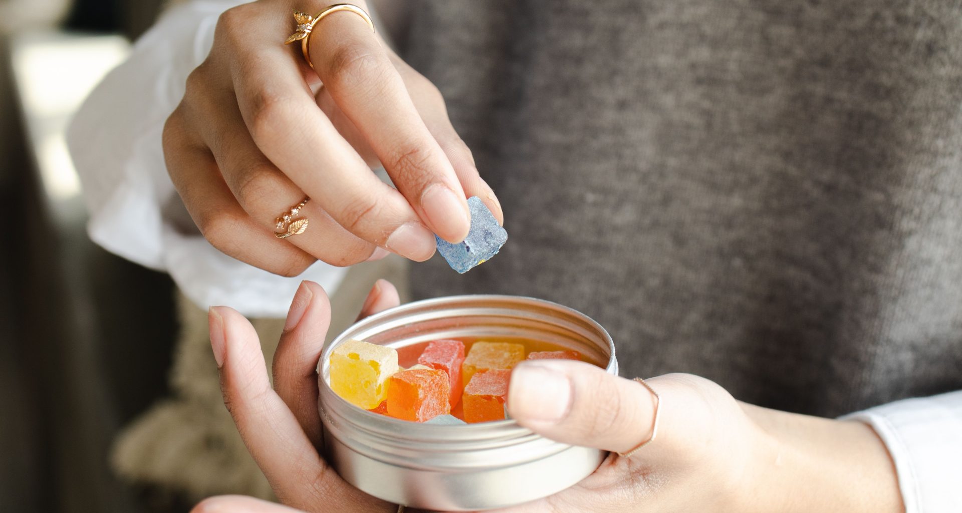 a person reaching into a container to take out a gummy supplement